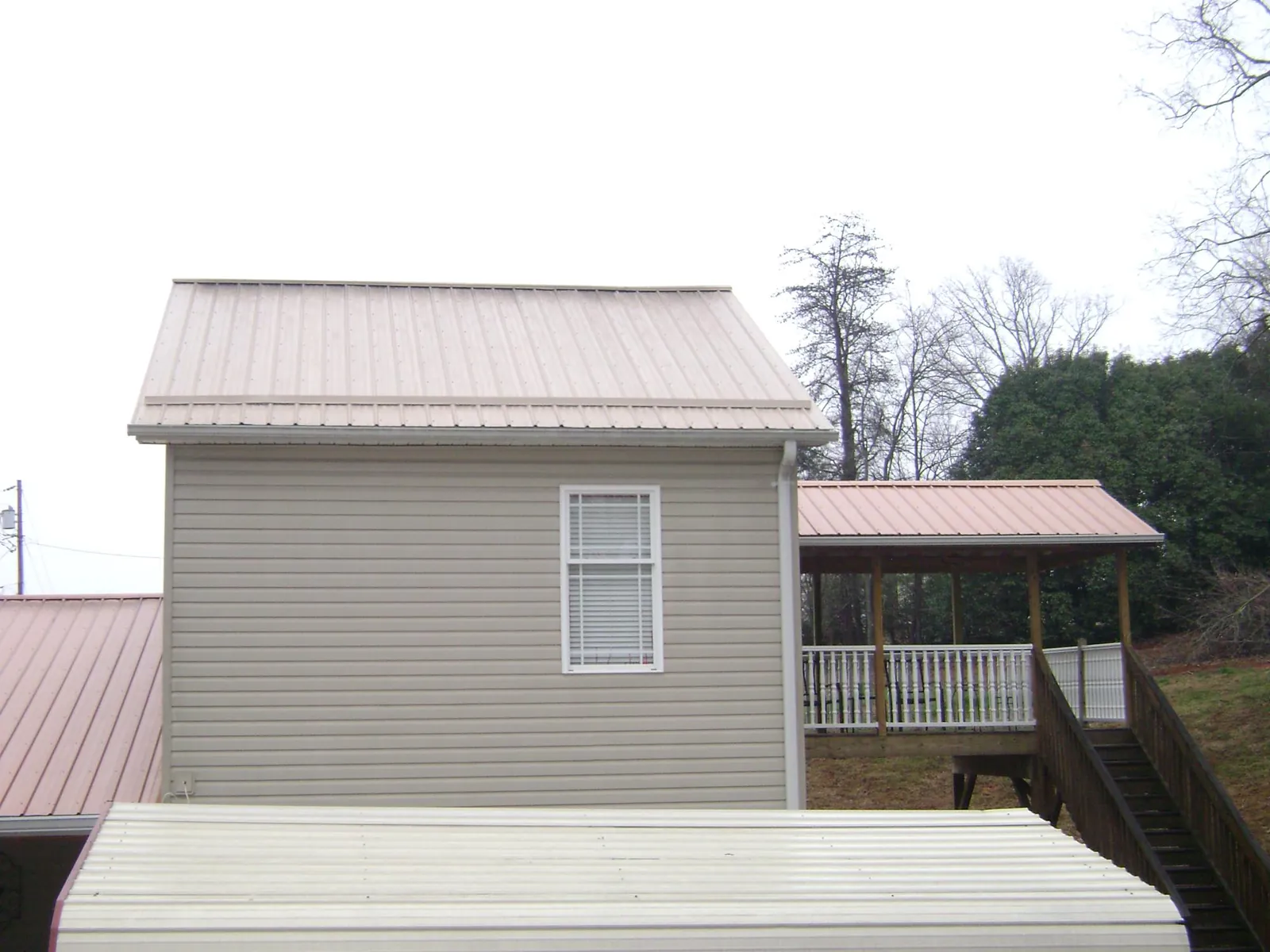 Tan metal roofs on a two story addition and attached porch, from a Roof Replacement job in Memphis